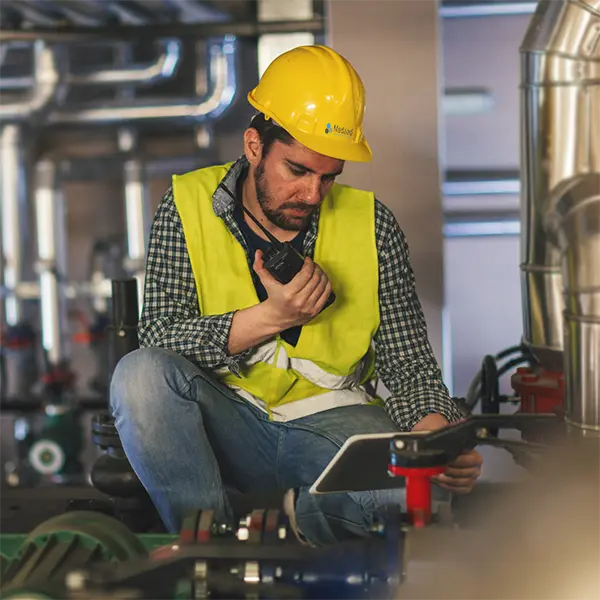 site engineer yellow hard hat vest talking on walkie talkie industrial gas piping